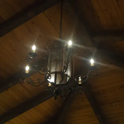 Sale Photo Thumbnail #125: Substantial Old World chandelier combining a central lantern with multiple scrolling candelabra arms. Ornate iron construction and dramatic scale make this an impressive foyer, dining, or great-room fixture. One of three coordinating fixtures available. B