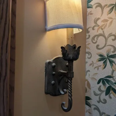 Sale Photo Thumbnail #9: Pair of rustic torch-style wall sconces with textured metal backplates, twisted stem detailing, decorative leaf accents, and small fabric shades. Well suited to traditional, Mediterranean, or Tuscan interiors.