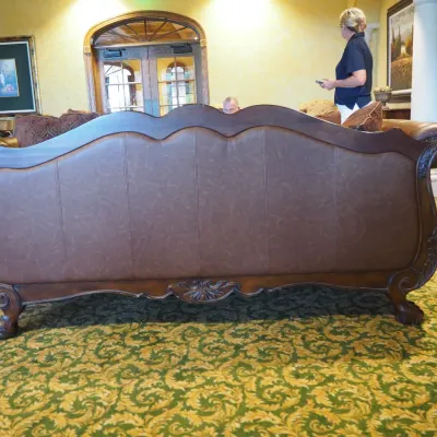 Sale Photo Thumbnail #107: Large traditional sofa upholstered in warm brown leather with oversized rolled arms, nailhead trim, carved wood base, and decorative scroll detailing. Includes coordinating oversized accent pillows and attractive aged character. 91w*38 deep* 41h