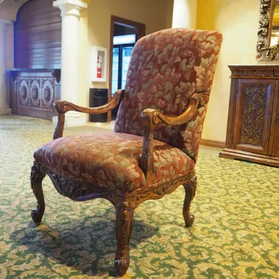 Sale Photo Thumbnail #110: Traditional high-back accent chair featuring richly patterned burgundy and muted green upholstery, carved wood arms, decorative apron, and cabriole-style legs. Substantial decorator-quality chair with classic Old World styling.