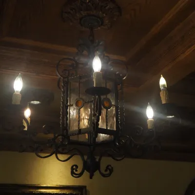 Sale Photo Thumbnail #126: Substantial Old World chandelier combining a central lantern with multiple scrolling candelabra arms. Ornate iron construction and dramatic scale make this an impressive foyer, dining, or great-room fixture. One of three coordinating fixtures available. B