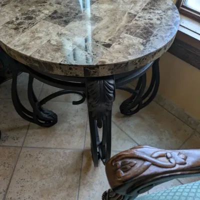 Sale Photo Thumbnail #24: Round accent table featuring a polished stone or marble-style top over an ornate black iron base with sculptural leaf and scroll detailing. A substantial decorator piece with strong Mediterranean styling. 23" round