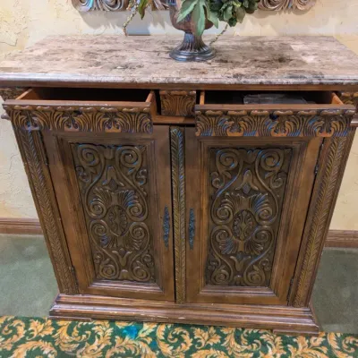 Sale Photo Thumbnail #33: Large traditional-style wood cabinet featuring deeply carved doors, decorative trim, upper drawers, and substantial molding throughout. Rich warm finish with an impressive architectural look. Ideal as a bar cabinet, storage cabinet, entry piece, or statem
