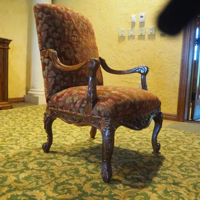 Sale Photo Thumbnail #111: Traditional high-back accent chair featuring richly patterned burgundy and muted green upholstery, carved wood arms, decorative apron, and cabriole-style legs. Substantial decorator-quality chair with classic Old World styling.