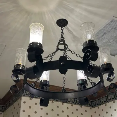 Sale Photo Thumbnail #95: Impressive oversized iron chandelier featuring a substantial circular frame, scrolling metalwork, chain suspension, and multiple cylindrical crackle-glass hurricane shades. Commercial-scale fixture with dramatic Old World styling. Buyer responsible for re