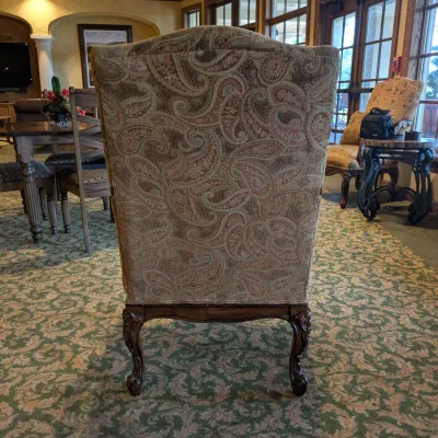 Sale Photo Thumbnail #139: High-back traditional armchair upholstered in a soft neutral paisley textile with carved wood arms, decorative apron, and cabriole-style legs. Attractive occasional chair with a more subdued palette than many of the clubhouse furnishings.
