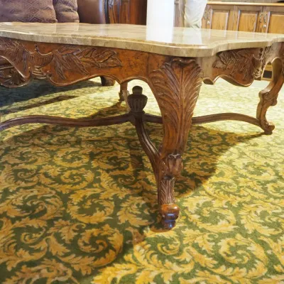 Sale Photo Thumbnail #99: Large statement coffee table featuring a shaped polished stone top over an extensively carved wood base with scrolling legs, leaf motifs, and decorative stretcher. Substantial construction and upscale traditional styling.