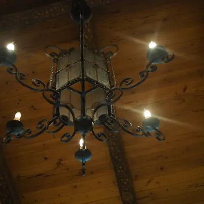 Sale Photo Thumbnail #123: Substantial Old World chandelier combining a central lantern with multiple scrolling candelabra arms. Ornate iron construction and dramatic scale make this an impressive foyer, dining, or great-room fixture. One of three coordinating fixtures available. B