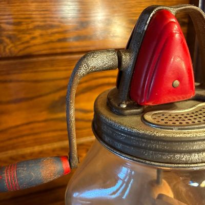 Sale Photo Thumbnail #744: This is a vintage Standard Churn Company (SCC) "Farm Master" 8-quart glass hand-crank butter churn, featuring a square jar, red-painted gear cover, and wooden paddles inside.