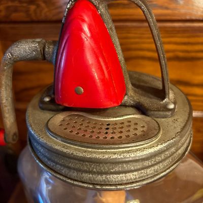Sale Photo Thumbnail #746: This is a vintage Standard Churn Company (SCC) "Farm Master" 8-quart glass hand-crank butter churn, featuring a square jar, red-painted gear cover, and wooden paddles inside.