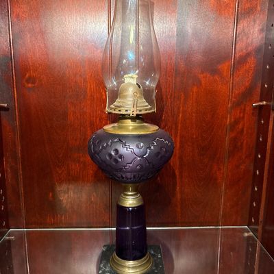 Sale Photo Thumbnail #555: antique Victorian amethyst glass and brass kerosene/oil lamp, likely dating to the late 19th century (circa 1860–1880s), featuring a patterned purple glass font, a brass connector, and a square marble base