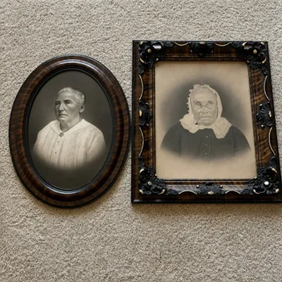 Sale Photo Thumbnail #124: Pair of antique portrait photographs of elderly women in period frames. The oval portrait is housed in a faux-grain wood frame and features distinctive convex “bubble” glass. The second portrait is presented in an elaborate rectangular faux-grain fram
