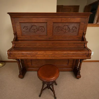 Sale Photo Thumbnail #11: Beautiful W.E. Wheelock & Co. upright piano featuring an unusually elaborate wood cabinet believed to have been custom handmade or extensively customized by the previous owner. The case displays striking figured wood grain, carved scrollwork panels, subst