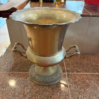 Sale Photo Thumbnail #302: This elegant brass champagne bucket measures approximately 9 inches by 9 inches, featuring a flared rim with intricate scrollwork detailing around the edge. The bucket is supported by a sturdy base adorned with ornate matching patterns, adding a classic a
