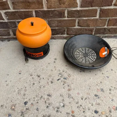 Sale Photo Thumbnail #217: This Lyman Turbo 1200 tumbler is designed for efficient cleaning and polishing of small parts, ideal for shooting enthusiasts. It features a bright orange, durable plastic drum with a secure lid, paired with a black base unit for stability. The accompanyi