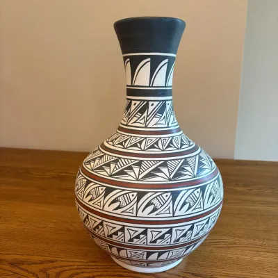 Sale Photo Thumbnail #26: This exquisite 15-inch tall and 10-inch wide ceramic vase is a fine example of Native American artistry, hand crafted and hand painted by Navajo artist Nelson Maloney. The vase features traditional black and white geometric patterns with intricate detaili