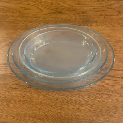 Sale Photo Thumbnail #259: This set includes four oval-shaped casserole dishes made from clear glass. The dishes vary in size, with diameters measuring approximately 10 to 12 inches and heights around 2 to 3 inches, making them perfect for baking, serving, and storing a variety of 