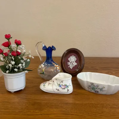 Sale Photo Thumbnail #281: This exquisite collectible features a hand-painted cobalt blue glass pitcher adorned with delicate floral motifs. Measuring approximately 5.5 inches in height, the pitcher showcases a clear glass handle and a ruffled spout. The intricate painted flowers i