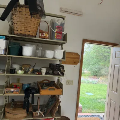 Sale Photo Thumbnail #201: This gardening supplies lot offers a diverse collection of essential items for gardening enthusiasts. Featuring multiple wooden trays, ceramic pots in white, glass jars, and various hand tools. The set includes large woven baskets, plastic green plant pot