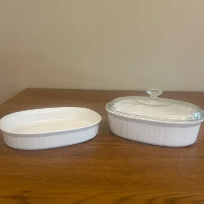 Sale Photo Thumbnail #264: This elegant set includes two white ceramic baking dishes, perfect for a variety of cooking and baking needs. The smaller dish measures approximately 11 inches in length and 2.5 inches in height, while the larger dish is slightly deeper at about 4.5 inche