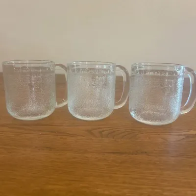Sale Photo Thumbnail #266: This set includes three LITTALA KROOVI beer mugs, uniquely designed by the renowned Finnish designer Oiva Toikka. Each mug is crafted from clear textured glass, measuring approximately 3.25 inches in height and 3.5 inches in diameter, making them perfectl