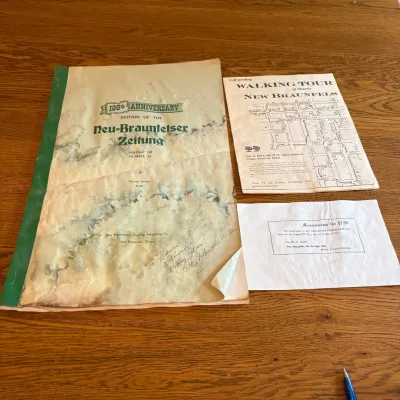 Sale Photo Thumbnail #29: This collectible features the 100th Anniversary Edition of The New Braunfelser Zeitung, showcasing historical significance and vintage charm. The edition includes a special cover marked with a green spine and aged, yellowed pages that highlight the paper'