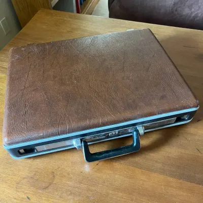 Sale Photo Thumbnail #308: This Samsonite Omega briefcase features a distinct brown leather exterior with visible wear, showcasing its authentic aged character. It includes a sturdy black handle and a reliable three-digit combination lock for secure closure. The interior is lined w