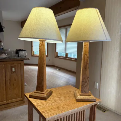 Sale Photo Thumbnail #161: This pair of Mission style table lamps features sturdy oak bases with a natural wood grain finish. Each lamp stands 36 inches tall and is topped with an 18-inch wide linen shade, providing a warm and inviting glow. The lamps combine classic craftsmanship 