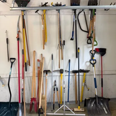 Sale Photo Thumbnail #208: This assortment of yard tools features a variety of essential gardening and outdoor maintenance equipment, including rakes, shovels, hoes, pruners, and brooms. The tools showcase sturdy wooden and metal handles, offering durability and comfortable grip. I