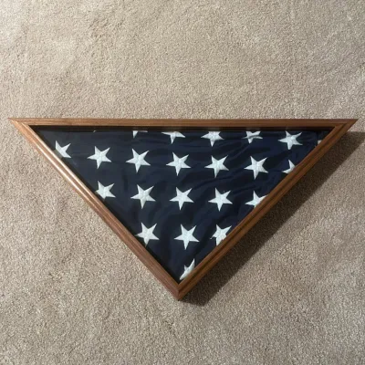 Sale Photo Thumbnail #51: This elegant triangular display case is designed to house and showcase a folded American flag, typically used for memorial or ceremonial purposes. It features a sturdy wooden frame with a natural finish that highlights the rich grain of the wood. The fron