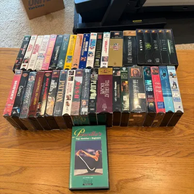 Sale Photo Thumbnail #73: This extensive VHS movie lot features a diverse collection of classic films along with a unique yoga instructional tape, Priscilla's Yoga Stretches for Beginners. The collection includes various genres, showcasing iconic titles in original VHS format, wit