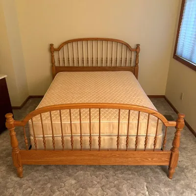 Sale Photo Thumbnail #167: This full-size bed features a classic wooden frame with vertical spindle detailing on both the headboard and footboard, showcasing a warm natural wood finish that adds a cozy and timeless appeal to any bedroom. Included is a Sealy Luxury Fashion Quilt Mat