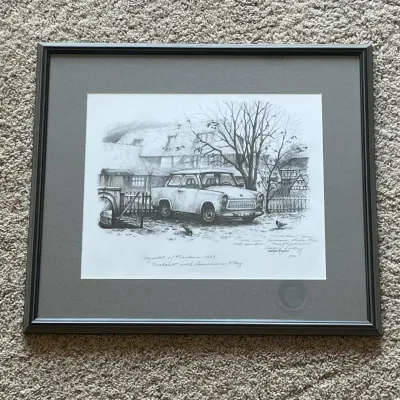 Sale Photo Thumbnail #43: Framed George A. Finley “Symbols of Freedom – 1989 Trabant with American Flag” print depicting an East German Trabant in Germany during the historic period surrounding the opening of the Berlin Wall.

The artwork is double signed: Finley’s signatu