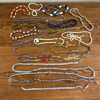 Sale Photo Thumbnail #331: A diverse collection of handmade beaded necklaces featuring an array of colors, sizes, and materials. This assortment includes vibrant glass beads, smooth wooden beads, and intricately decorated ceramic beads. The necklaces showcase a variety of textures 