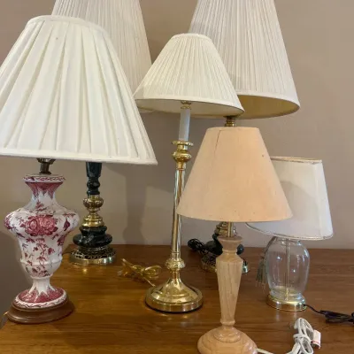 Sale Photo Thumbnail #158: This collection features assorted table lamps showcasing a variety of unique designs and materials. Included are lamps with elegant pleated white shades, intricate bases in brass, marble, and ceramic finishes, and diverse color schemes including red flora