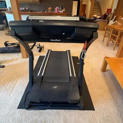 Sale Photo Thumbnail #218: This NordicTrack E 4400 treadmill features a robust black and silver frame with a spacious running belt designed for comfortable workouts. It includes an advanced digital console with multiple function buttons, clear display screens, and integrated speake