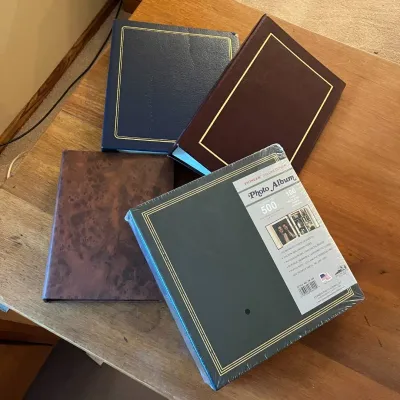 Sale Photo Thumbnail #313: This collection features four photo albums, each with a unique cover design perfect for preserving your memories. Included are albums in deep navy blue, rich burgundy, a marbled brown, and a green album with a classic gold-bordered cover that comfortably 