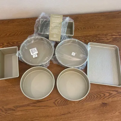 Sale Photo Thumbnail #138: This Gold Touch Williams Sonoma Baking Set includes an assortment of high-quality baking pans perfect for various baking needs. The set features round cake pans, loaf pans, a square pan, and a rectangular baking pan all with a smooth gold-tone finish. Eac