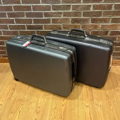 Sale Photo Thumbnail #224: This vintage American Tourister suitcase set features two sturdy hard shell cases in classic black, designed for durability and style. Each case includes a secure combination lock and key lock mechanism for added security. The interiors are lined with a l