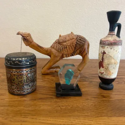 Sale Photo Thumbnail #275: This finely crafted wooden camel figurine features detailed hand-carved patterns depicting a traditional saddle and decorative elements. Measuring approximately 11 inches in length and 8 inches in height, the figurine showcases a natural wood finish that 