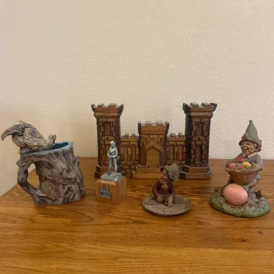 Sale Photo Thumbnail #278: This intricately designed medieval castle collectible is handcrafted from rich, dark wood, showcasing detailed brickwork and battlements. Measuring approximately 12 inches wide, 9.5 inches tall, and 2.5 inches deep, it serves as a striking centerpiece for