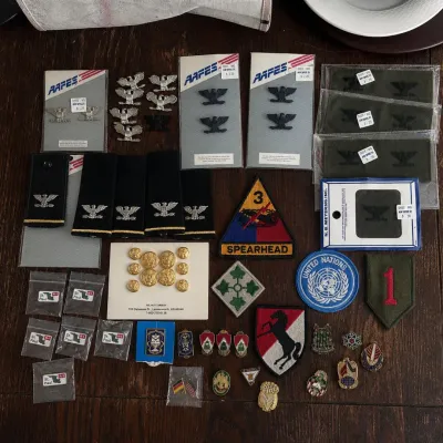 Sale Photo Thumbnail #63: Large assorted collection of U.S. Army military insignia, rank devices, shoulder patches, unit pins and uniform accessories from the personal collection of a former U.S. Army battalion commander.

The group includes numerous Colonel eagle rank insignia in