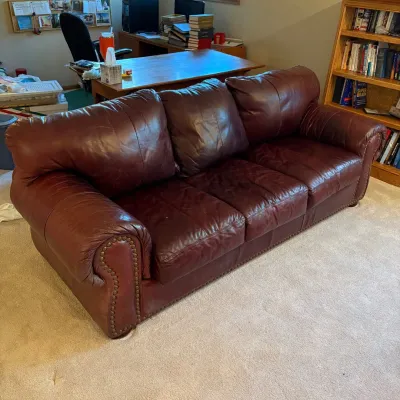 Sale Photo Thumbnail #180: This brown leather couch features a rich, warm tone and a durable leather material that offers both comfort and style. Measuring 34 inches tall, 90 inches wide, and 36 inches deep, it provides ample seating space for a living room or office. The couch is 