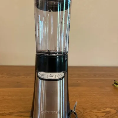 Sale Photo Thumbnail #236: This Cuisinart compact portable blending and chopping system is designed for versatile kitchen use. It features a sleek stainless steel and black plastic body, combining durability with modern aesthetics. Standing approximately 12 inches tall and 3.5 inch