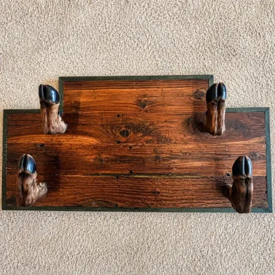 Sale Photo Thumbnail #33: Unique rustic wall-mounted rack featuring four preserved deer hooves/feet mounted to a substantial wood backing with a stepped top profile and dark green trim. The hooves project outward to function as hooks, making the piece suitable for displaying hats,