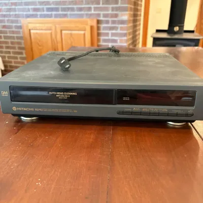 Sale Photo Thumbnail #68: This Hitachi M240 DA 4-head VCR features digital auto tracking and multiple input/output options, including composite and coaxial connectors. It is a sturdy unit with a black exterior, designed for standard VHS cassette tapes. Please note, the cassette me