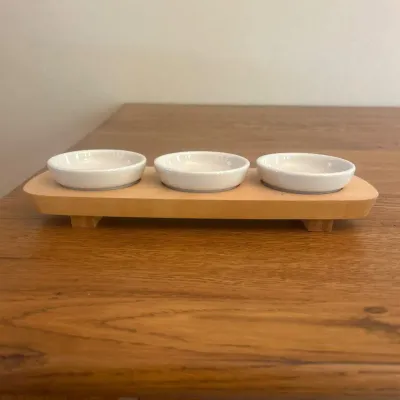 Sale Photo Thumbnail #149: This Longaberger dipping set features three small white ceramic bowls securely placed on a natural wood base, measuring approximately 13 inches in length and 4.5 inches in width. The bowls are about 3.25 inches in diameter, making them perfect for serving