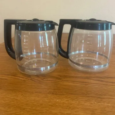 Sale Photo Thumbnail #255: This set includes two authentic Cuisinart coffee pots, perfect for brewing and serving your favorite coffee. Each coffee pot is made of clear glass, allowing you to easily monitor the coffee level. They feature sturdy black plastic lids with a central kno