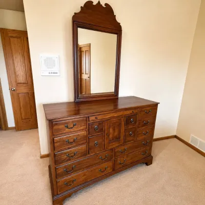 Sale Photo Thumbnail #186: Quality Lexington Furniture dresser with matching mirror from The World of Bob Timberlake collection. Features a warm cherry-toned wood finish, numerous drawers in varying sizes, a central paneled cabinet, traditional dark metal hardware, and a large matc