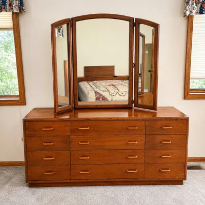 Sale Photo Thumbnail #169: This elegant wooden tri-fold dresser features a unique curved arched center panel in the mirror, adding a sophisticated touch to any bedroom. Crafted with a rich cherry finish, the dresser combines style and functionality with multiple drawers for ample s